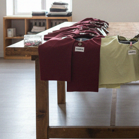 Eco leather Bulb Bag pieces in burgundy and green laid on a wooden table inside the Bucharest handmade studio during the crafting process.

