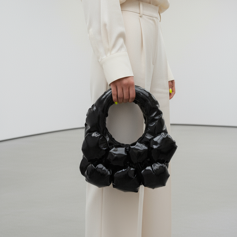 Person holding a black handbag in a minimalistic setting